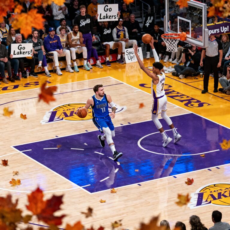 Luka Doncic of the Lakers drives to the basket against Victor Wembanyama of the Spurs during a high-stakes NBA game with a cheering crowd.