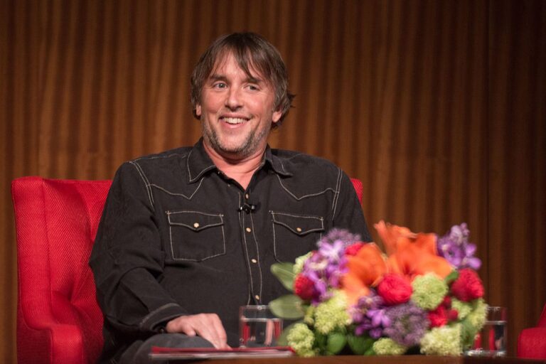 Portrait of acclaimed filmmaker Richard Linklater, captured in a candid moment with a thoughtful gaze, short hair, and casual attire against a neutral background, highlighting his signature introspective demeanor.